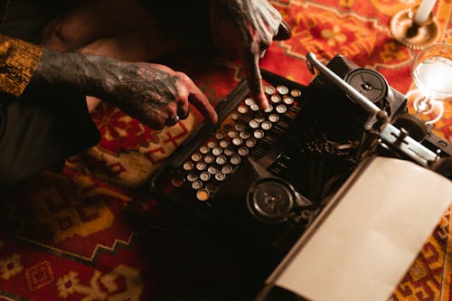 Tattooed Person Typing on Typewriter