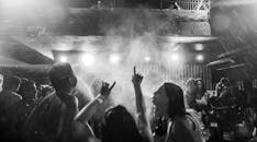 一张动态的黑白图像捕捉了夜总会里人群在烟雾和灯光中热情舞动的场景