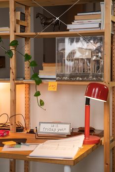 A stylish and organized workspace featuring a wooden desk, red lamp, and decorative shelving.