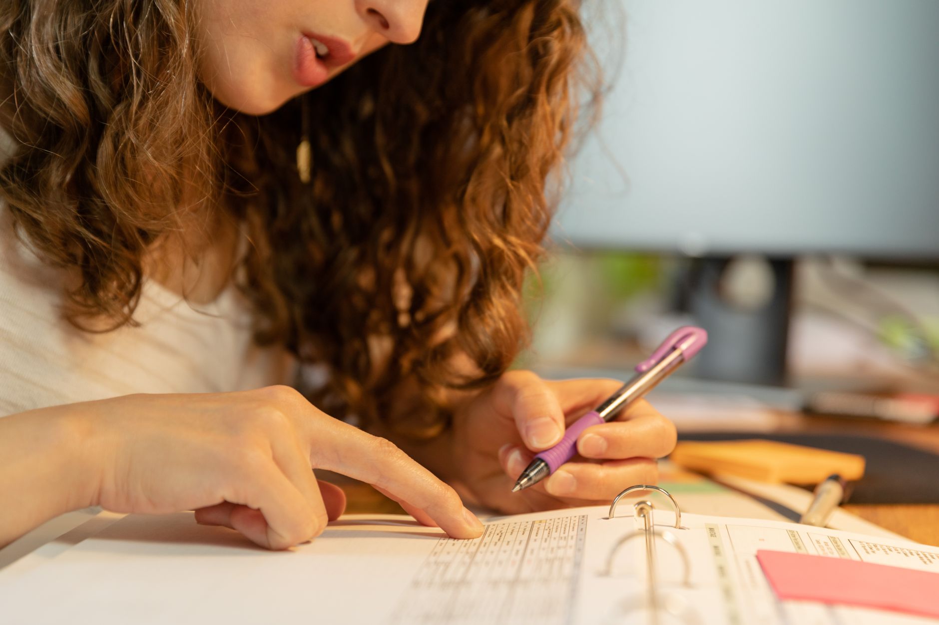 Hands going through printed notes with a pen, reviewing which packages are worth running again