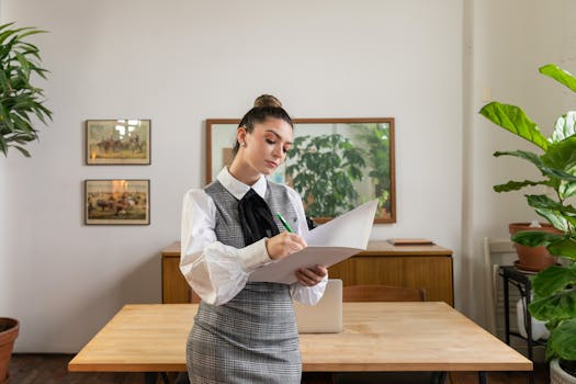 Businesswoman writing notes in a stylish office setting with plants and decor.