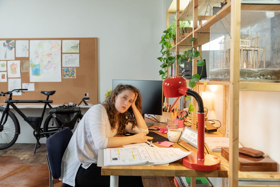 Ultimate Beginner's Guide to Setting Up Automated Lighting Schedules (2025) Tired businesswoman working at a cluttered desk, surrounded by office supplies and plants.