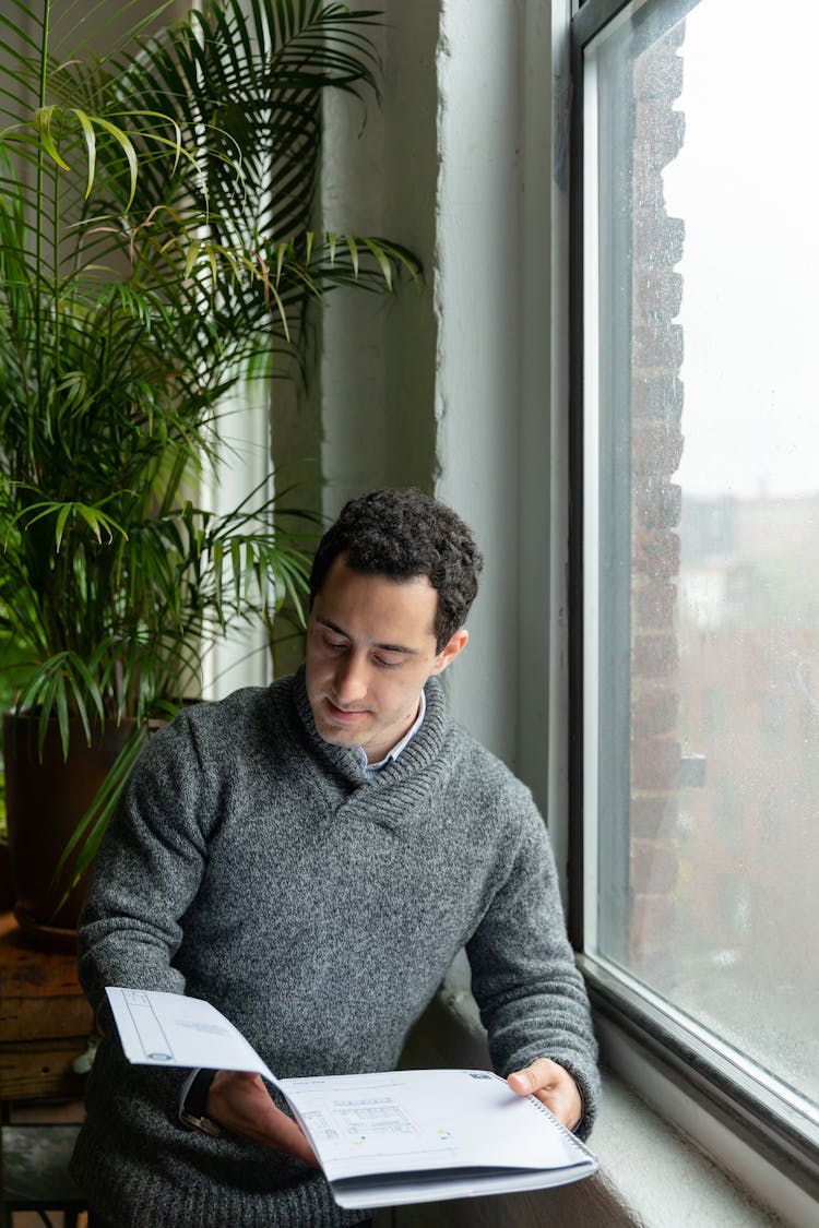 Man Reading Document Next To A Window