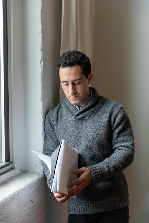 A Man in Gray Sweater Holding a Folder