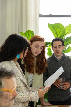 Diverse business team engaged in a collaborative meeting, discussing documents in a bright office space.