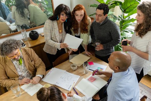 A diverse team discusses documents around a table in a modern office setting, promoting teamwork and collaboration.