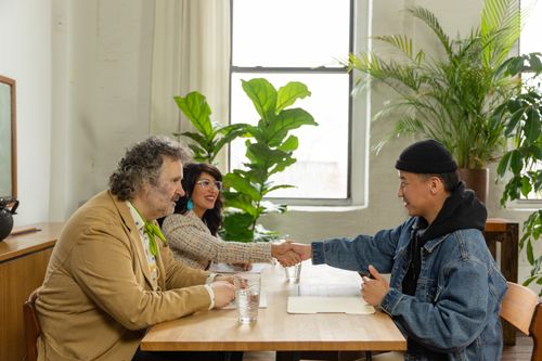 Free Diverse group of business people shaking hands in an office setting with indoor plants. Stock Photo
