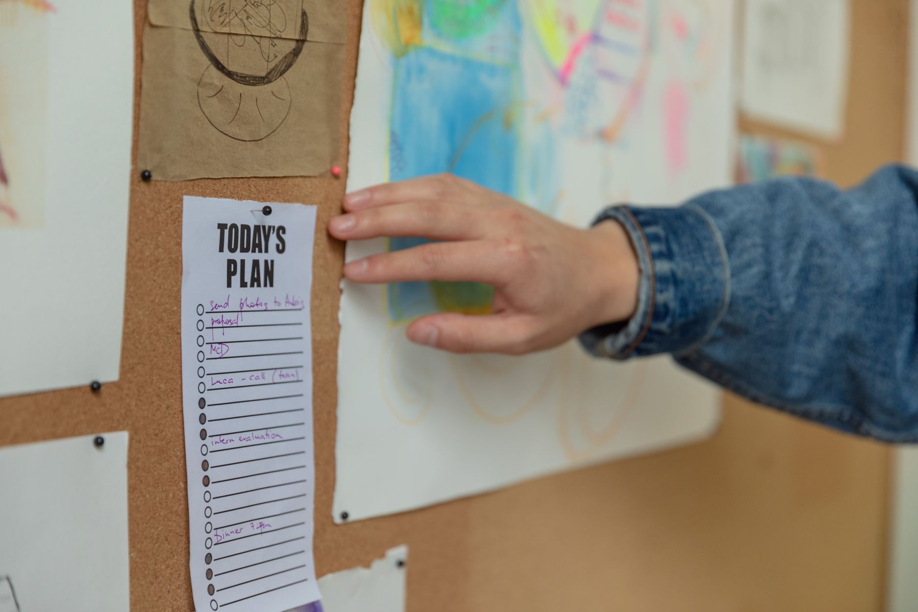 Hand pinning to-do list on corkboard, planning and organization concept.