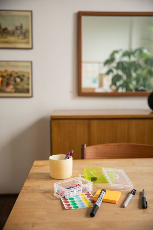Free A cozy indoor scene with stationery items on a wooden table and a reflection of greenery. Stock Photo