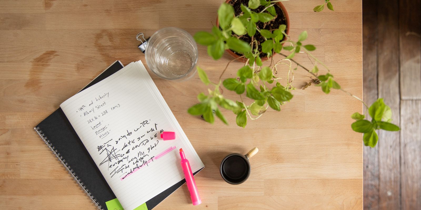 Overhead view of a workspace with notebooks, plant, and highlighter.
