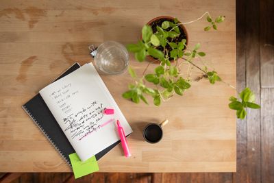Overhead view of a notebook, plant and highlighter on a wooden desk — photo by RDNE Stock project on Pexels