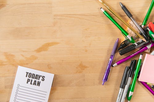 Notepad and Pens on Wooden Surface