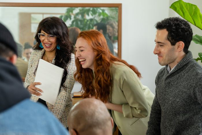 Colleagues laughing over printed pages, photo by RDNE Stock project on Pexels