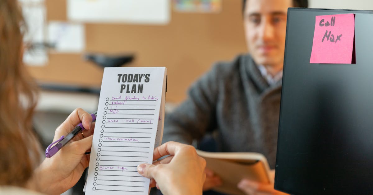 Two colleagues organizing tasks with a plan and sticky notes during a team meeting.