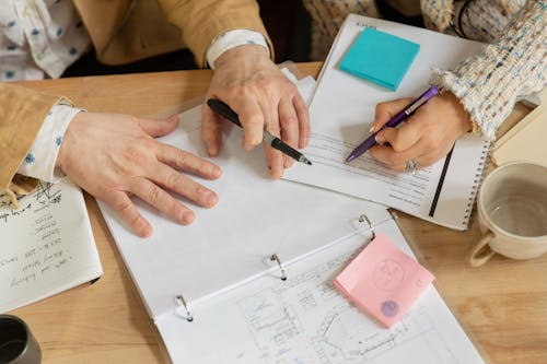 Close-up of People Sitting at the Desk, Reading and Writing in Documents 