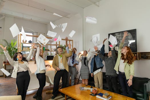 A diverse group of office coworkers celebrating by throwing papers in the air.