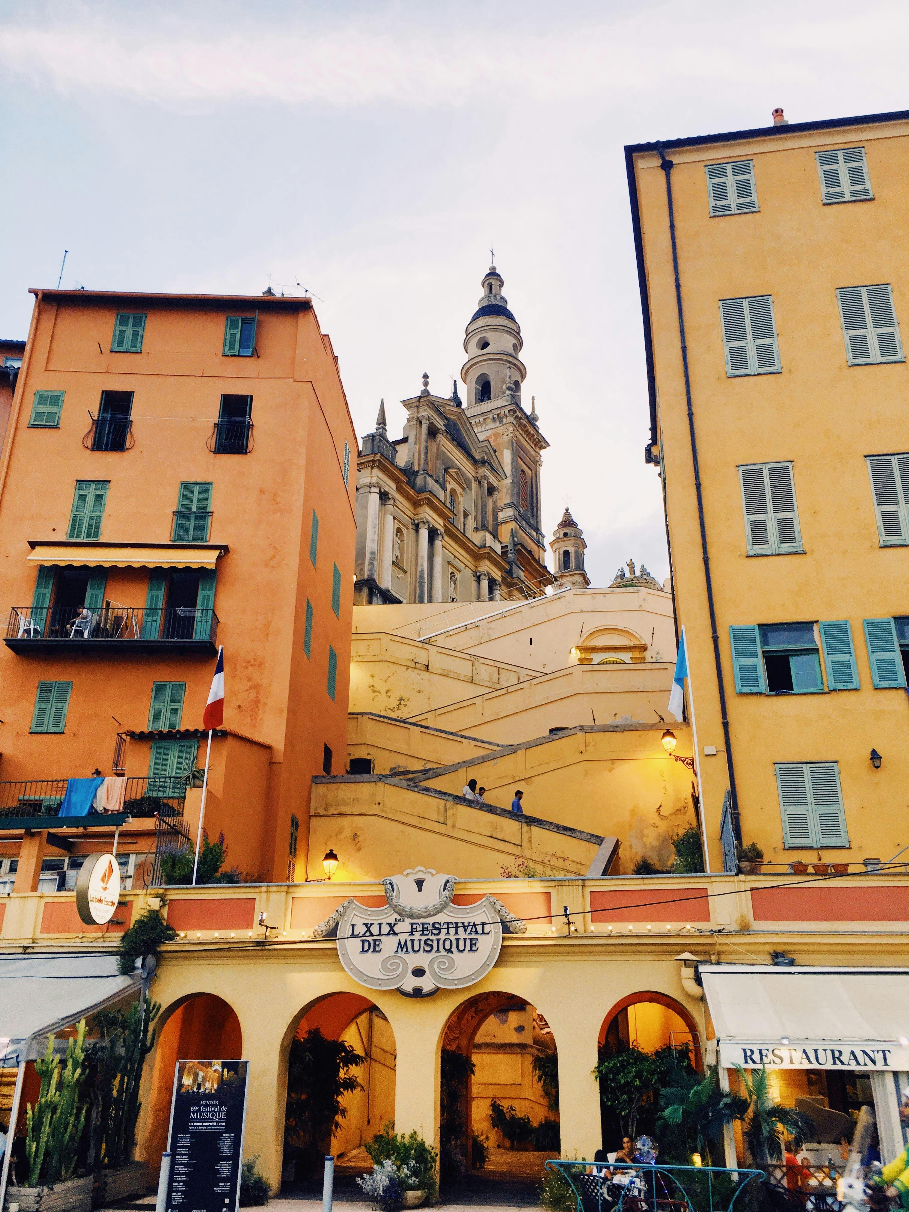 Exterior of aged residential building with ornamental balconies and facade of arched passage of store with sign