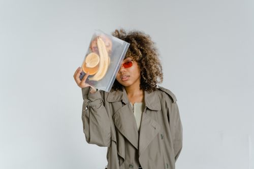 Free Stylish woman with curly hair holding a bag of fresh fruits against a white background. Stock Photo