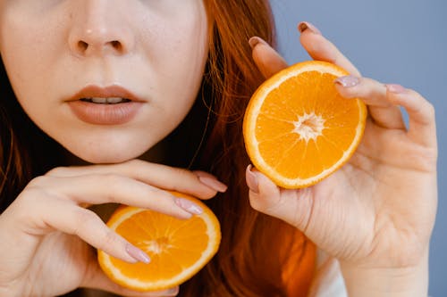 Free Woman Holding Slices of Orange Fruit Stock Photo