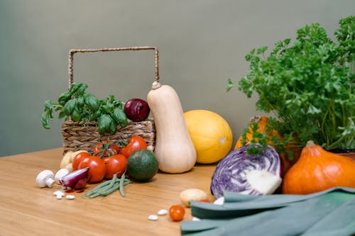 Assorted Vegetables in a Basket and on a Wooden Table