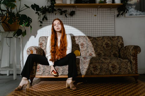 A Woman in White Long Sleeves Sitting on a Couch 