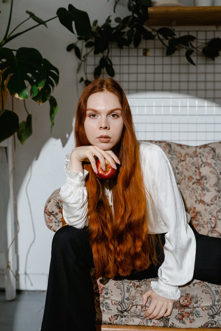 A Woman With Red Hair Holding An Apple