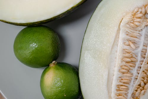 Close-up Shot of Green Limes and a Cantaloupe Cut in Half