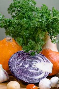 A vibrant display of fresh vegetables including red cabbage, squash, and herbs.
