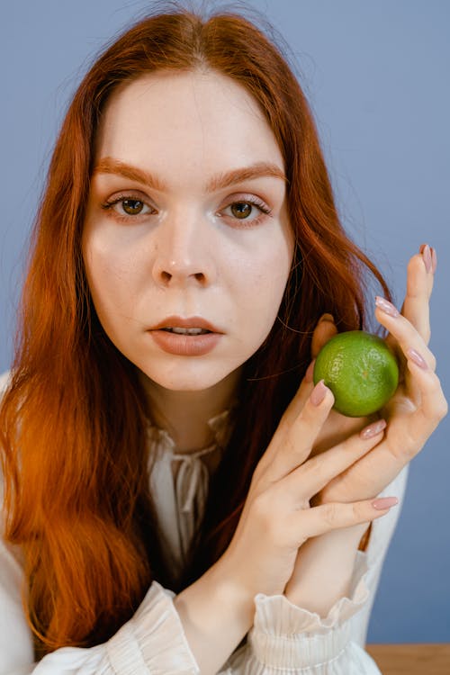 Woman Holding Green Citrus Fruit