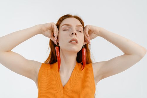 Free Caucasian woman with eyes closed, wearing chili pepper earrings in a studio shoot. Stock Photo