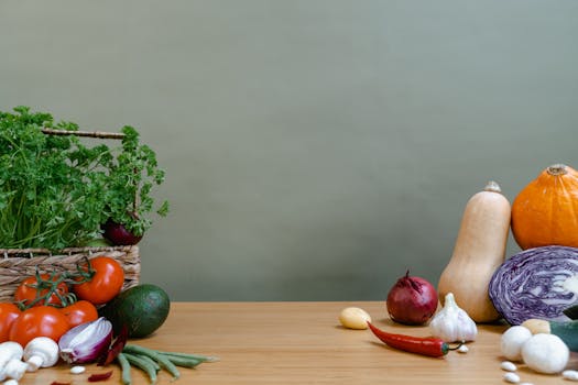Assorted fresh organic vegetables including tomatoes, garlic, and pumpkins on a wooden table.