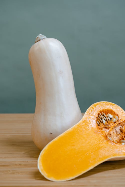 Whole and a Sliced Butternut Squash on a Wooden Surface