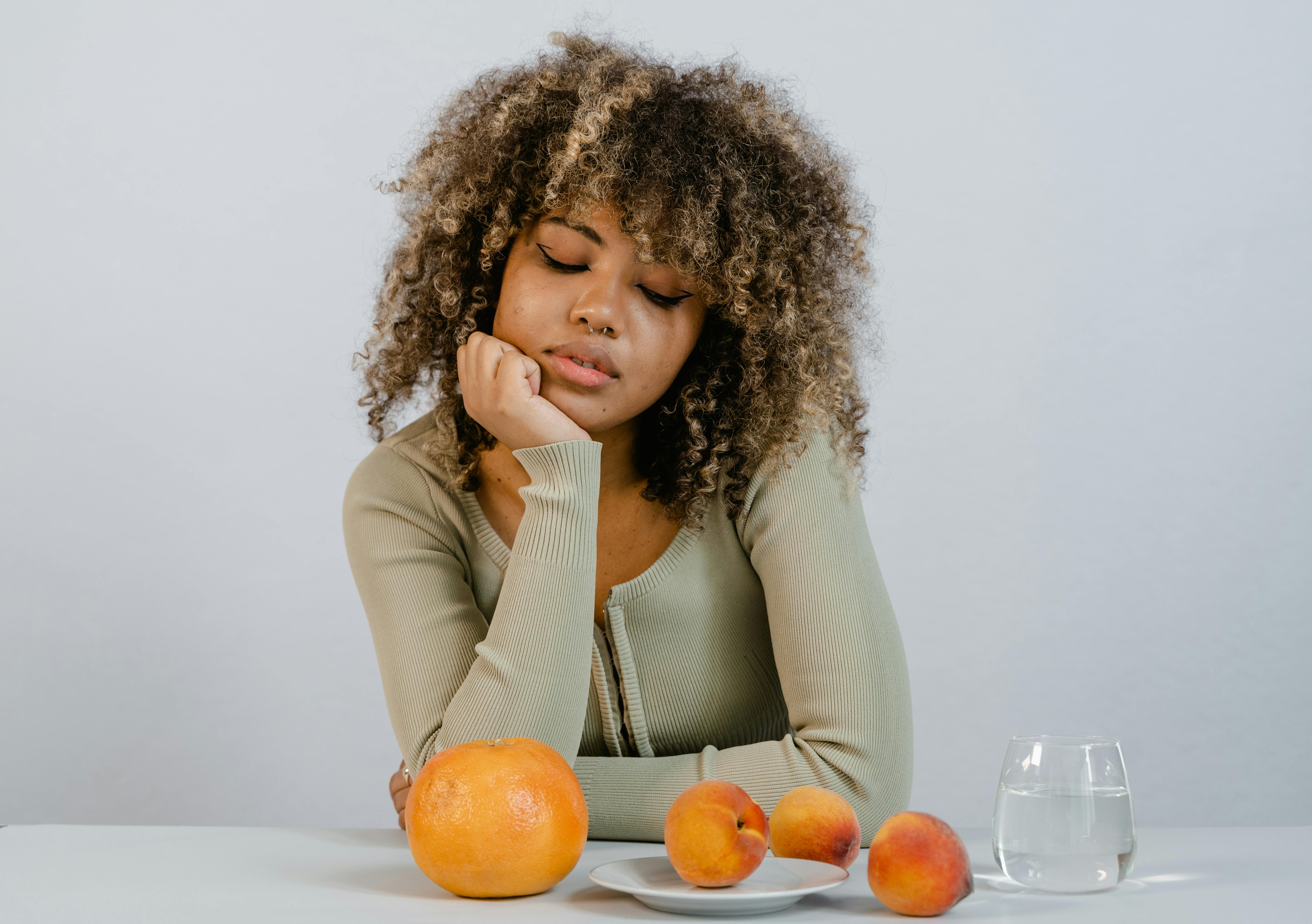 a woman in green long sleeves looking at fresh fruits