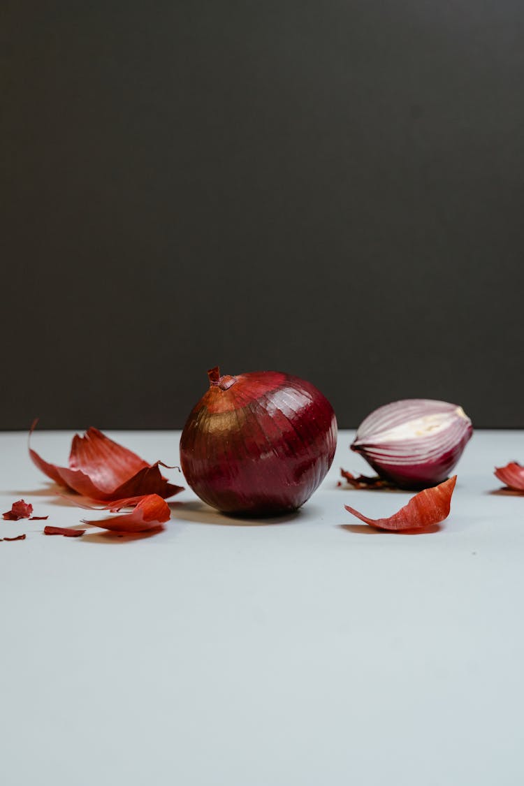 An Onion With Skin On A White Surface