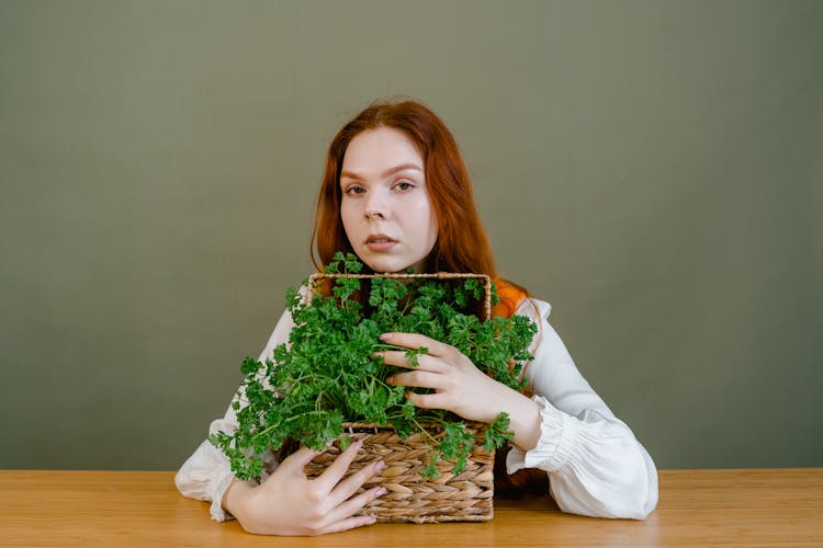 Woman Holding A Woven Basket With Green Vegetables