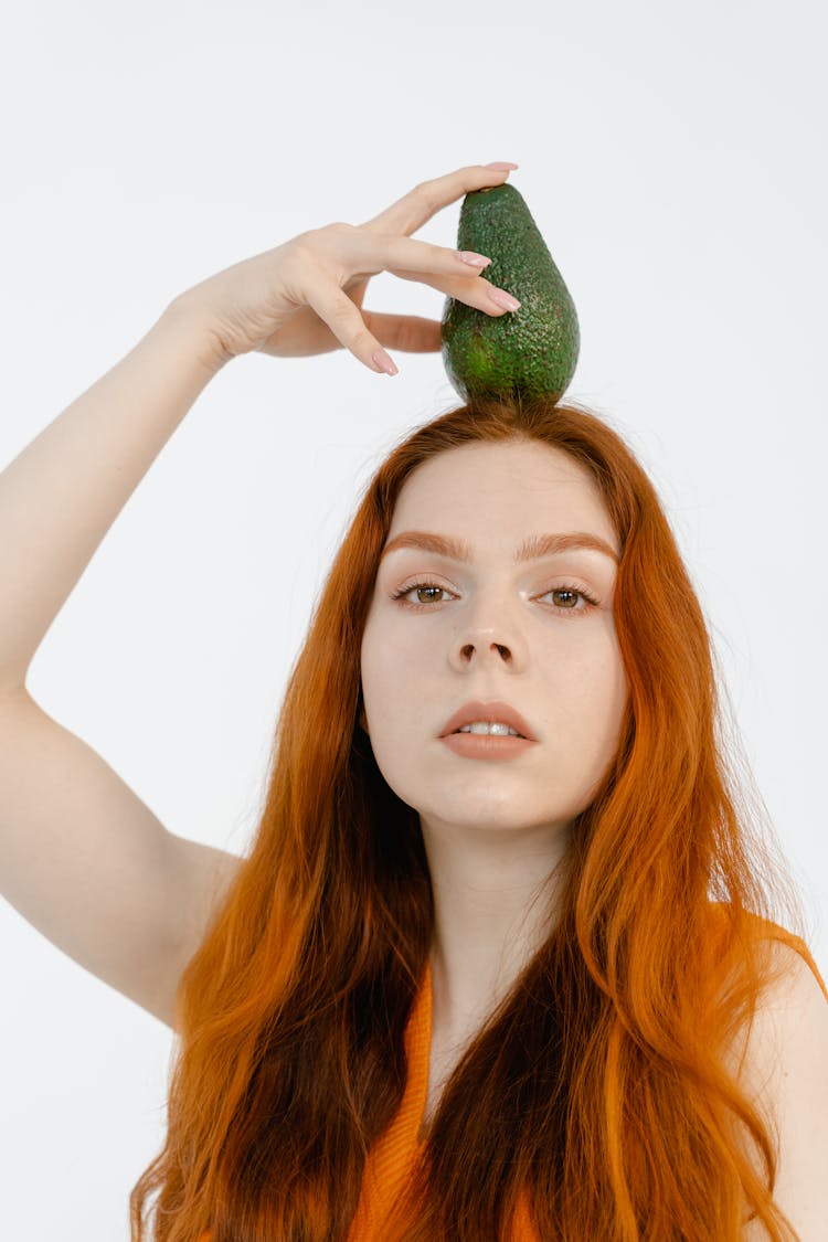 A Woman Holding An Avocado On Her Head