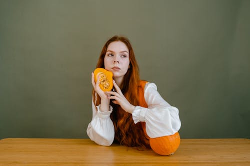 Free A Woman Holding a Pumpkin Cut in Half Stock Photo