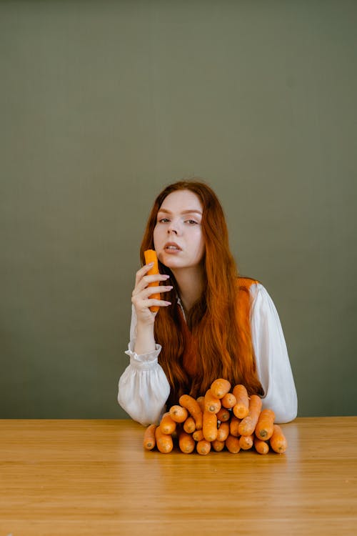 A Woman in White Long Sleeves Holding a Carrot
