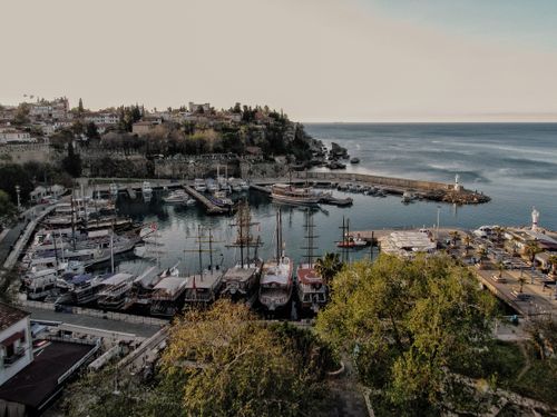 Free Aerial view of a picturesque harbor with boats docked and a coastal town backdrop. Stock Photo