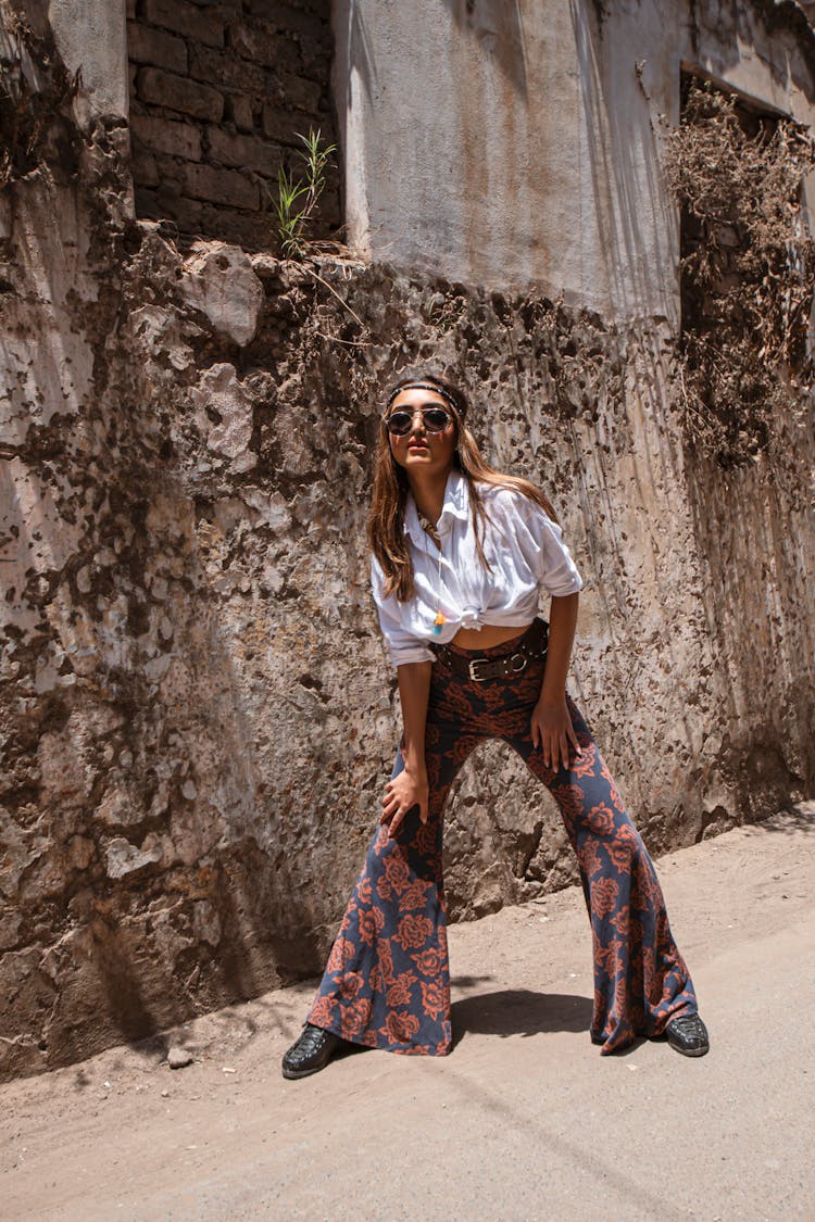 Woman In Bell Bottom Pants Near A Wall