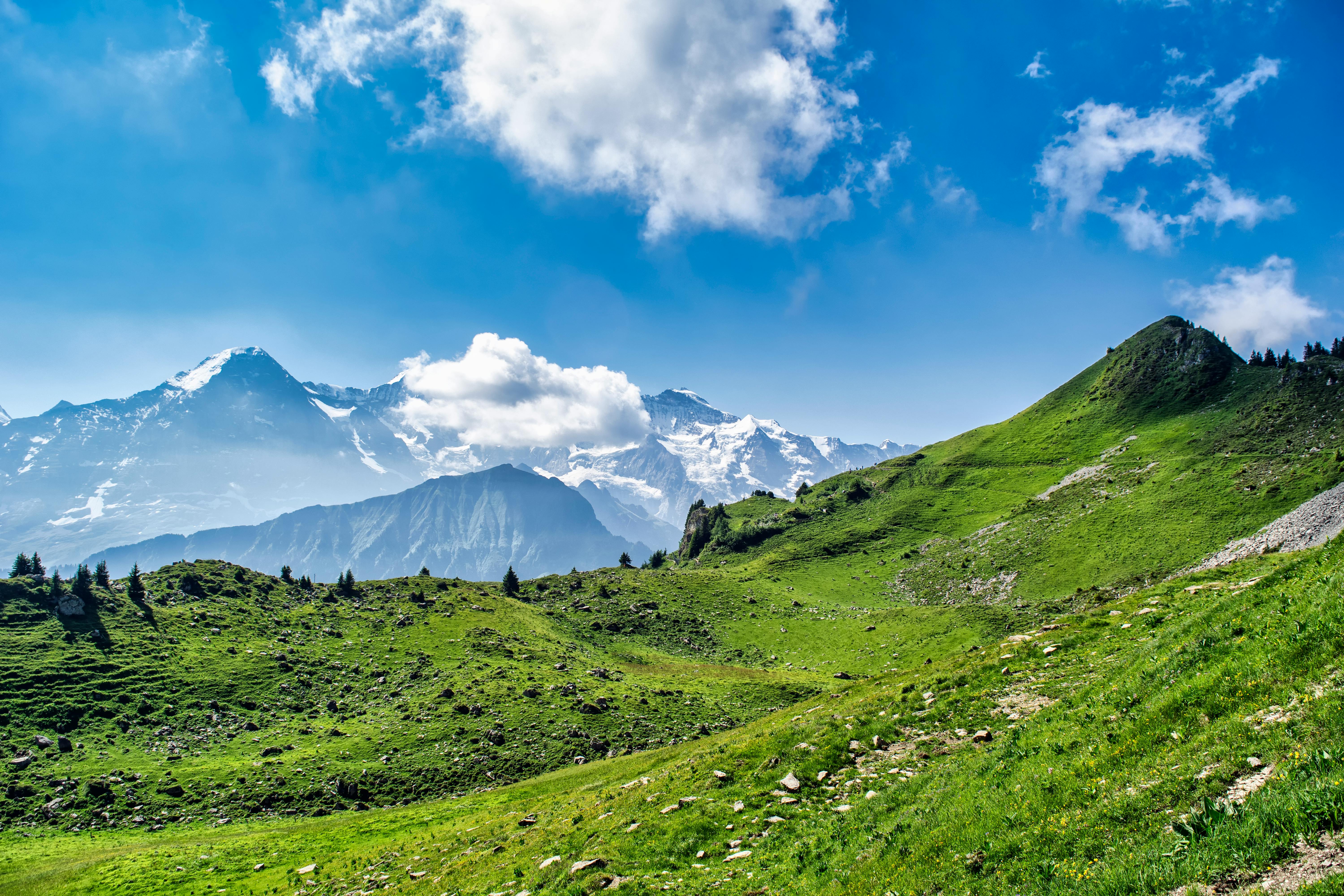 Green Grass Field and Mountains Under Blue Sky · Free Stock Photo