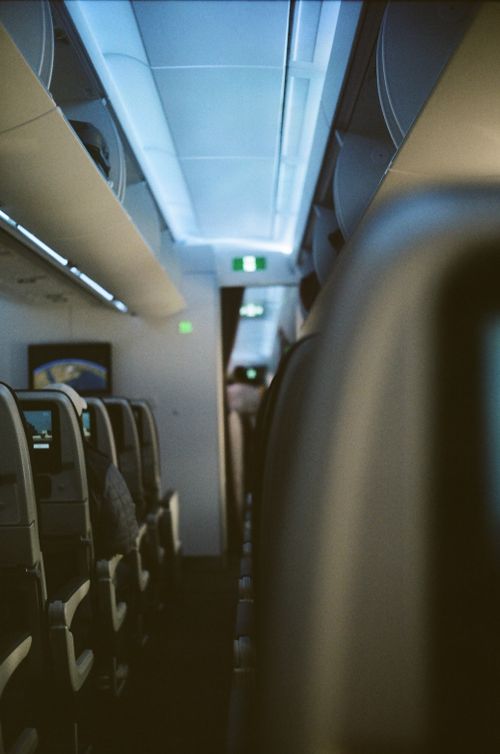 Free A cozy and ambient view of an airplane cabin in flight, showcasing rows of seats and overhead compartments. Stock Photo