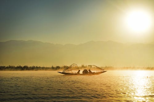 Группа людей катается на лодке посреди воды во время восхода солнца