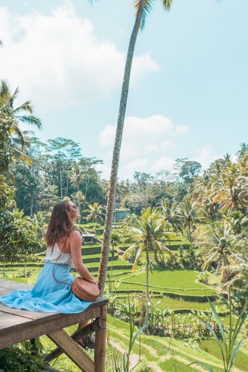 Woman in Skirt Sitting with Tropical Forest with Palm Trees behind