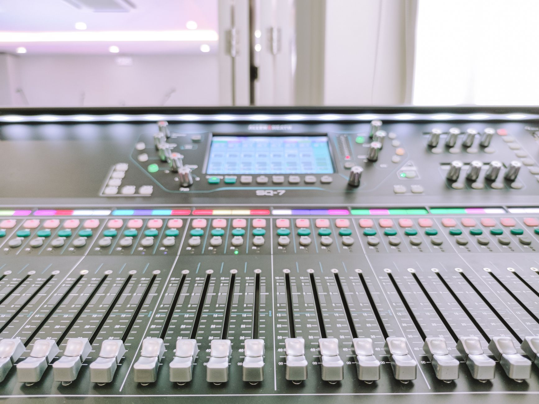 Close-up view of a digital audio mixer in a recording studio environment.