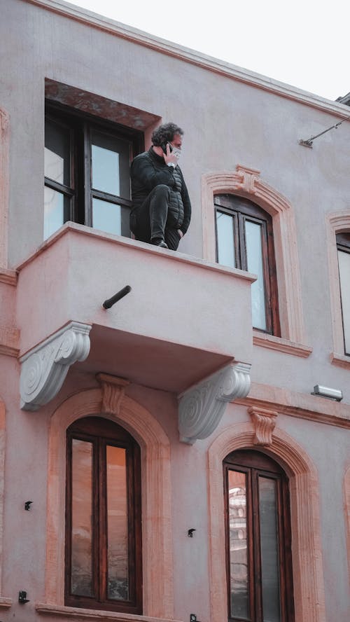 Free Unrecognizable man having phone conversation on balcony Stock Photo