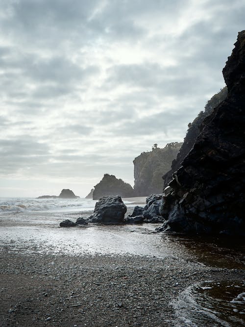 Rock Mountains Under a Cloudy Sky in Grayscale Photography