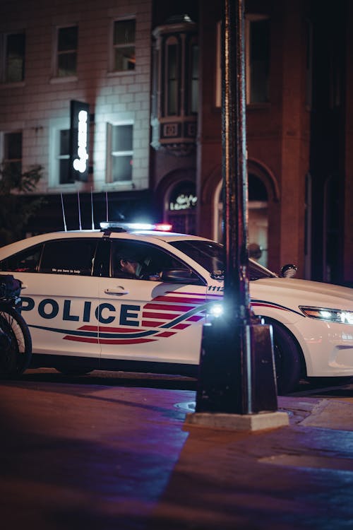 Free White and Black Police Car on Road during Night Time Stock Photo