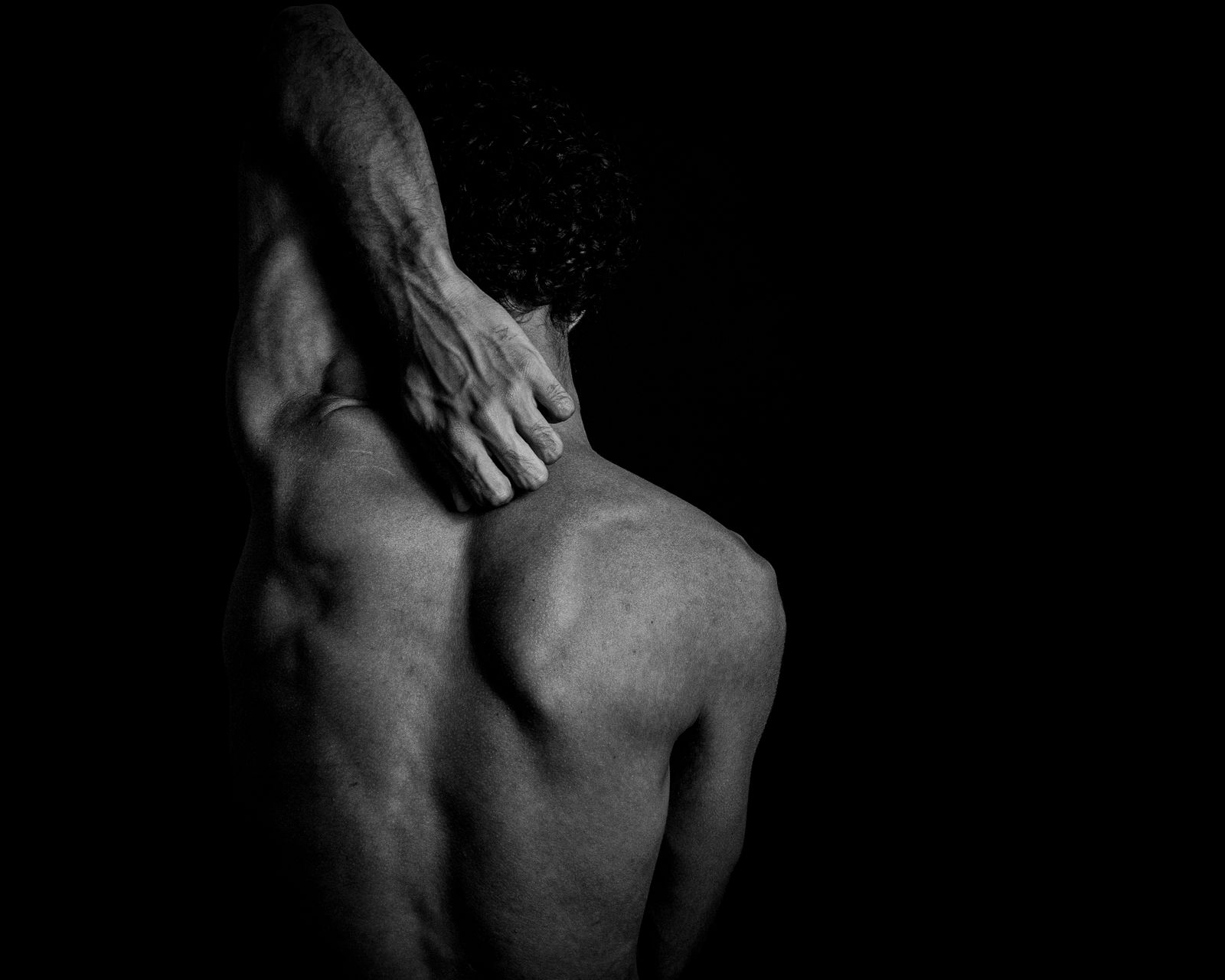 Adult stretching outdoors with hands on lower back in bright daylight