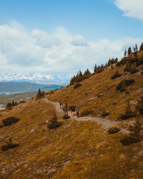 People Walking on a Dirt Pathway Along the Mountain